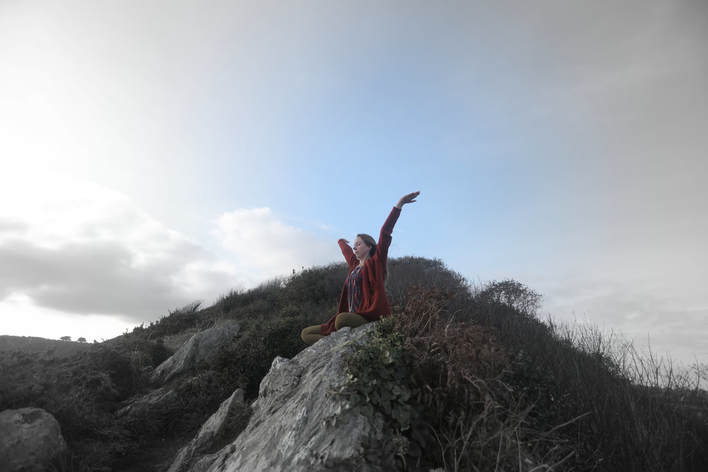 Teja Kaur doing pranayama breath meditation sitting on a cliff in falmouth cornwall